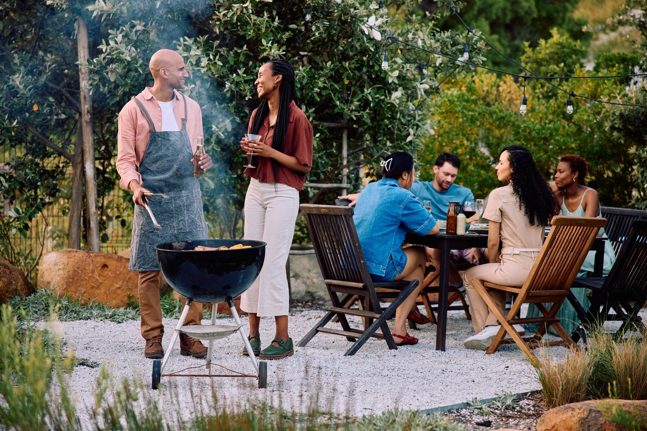 Friends gathered around an outdoor barbecue grill